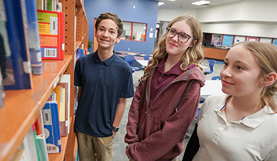 Three happy QCUSD students in a library